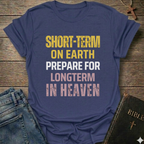 Purple  t-shirt with text "Short Term on Earth Prepare for Long Term in Heaven" Christian T-Shirt bold faith apparel conversation starter, on a wooden surface with jeans and a Bible.